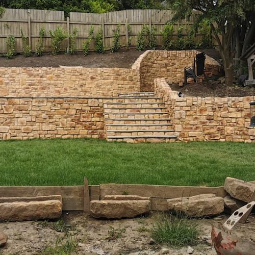 Stone cladding wall with steps in a landscaped garden, showcasing the natural aesthetic of stone slips.