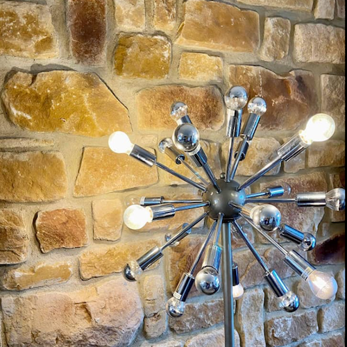 Modern lamp design in front of a rustic stone cladding wall featuring natural stone textures and warm tones.