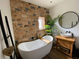 Elegant bathroom featuring Antique Blend Stone Cladding, freestanding bathtub, and wooden vanity with plants.