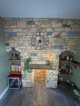 Rustic stone cladding fireplace with a large clock and shelves, showcasing natural stone textures in a cozy interior.