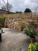 Outdoor patio with antique blend stone cladding wall and decorative plants in pots.
