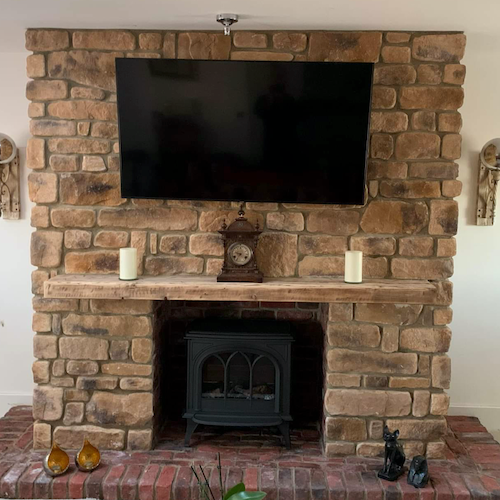 Stone cladding wall with fireplace and TV, featuring a rustic design and natural aesthetics in a cozy living space.