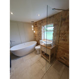 Modern bathroom featuring stone cladding walls, a freestanding bath, and a stylish vanity with natural light.