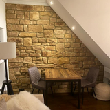 Stylish interior featuring Cotswold Blend stone cladding wall, wooden table, and contemporary chairs.
