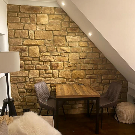 Stylish interior featuring Cotswold Blend stone cladding wall, wooden table, and contemporary chairs.