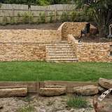 Stone cladding wall with steps in a landscaped garden, showcasing the natural aesthetic of stone slips.