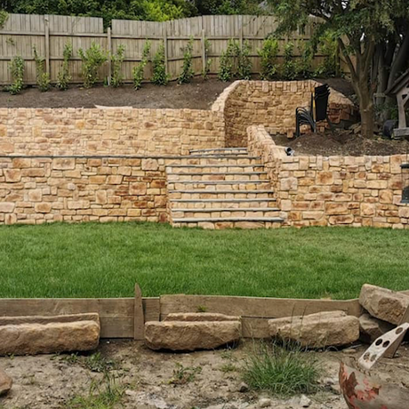 Stone cladding wall with steps in a landscaped garden, showcasing the natural aesthetic of stone slips.