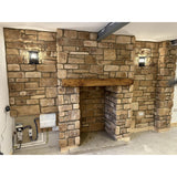 Stone cladding installation in a cozy living space featuring Cotswold Blend stone slips and rustic wall lighting.