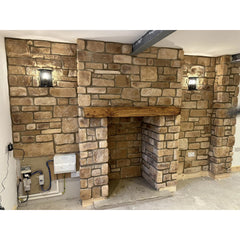 Stone cladding installation in a cozy living space featuring Cotswold Blend stone slips and rustic wall lighting.