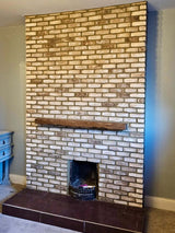 Rustic cream blend brick slips create a stylish fireplace with a wooden mantel in a cozy living room setting.