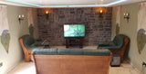 Living room featuring stone cladding wall, dark green sofas, and a TV, showcasing a cozy atmosphere with natural aesthetics.