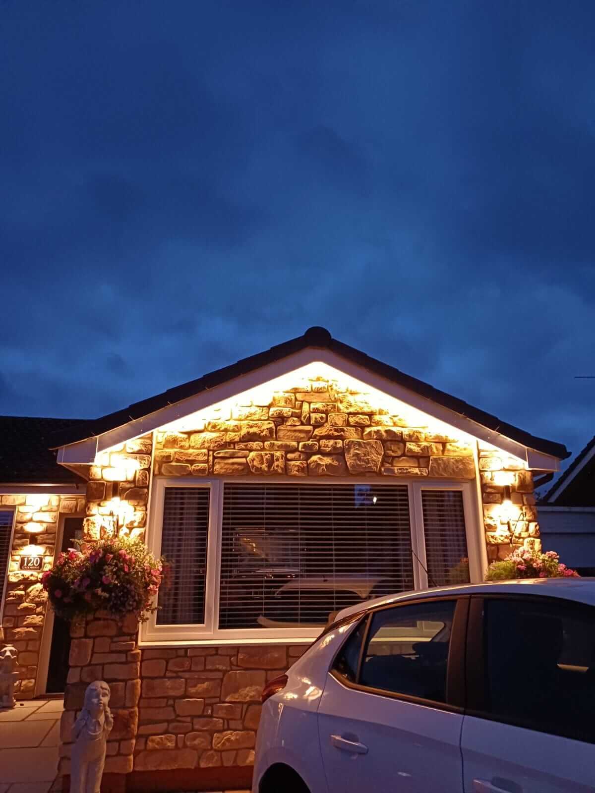 Stone cladding on a home exterior with decorative lighting, showcasing a cozy evening ambiance.