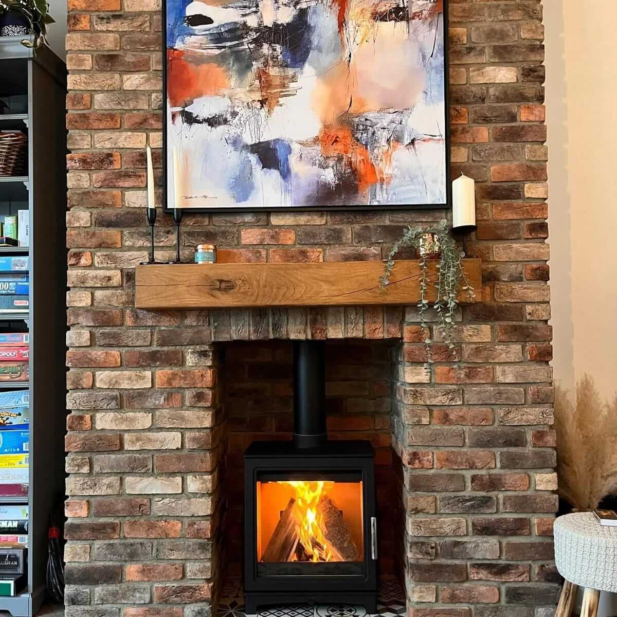 Cozy living room featuring a stylish brick fireplace with an art piece above and glowing fire.