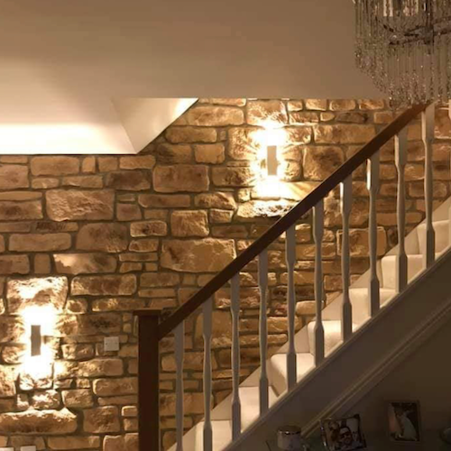 Elegant staircase featuring Cotswold Blend Stone Cladding, enhanced by warm lighting for a natural aesthetic.