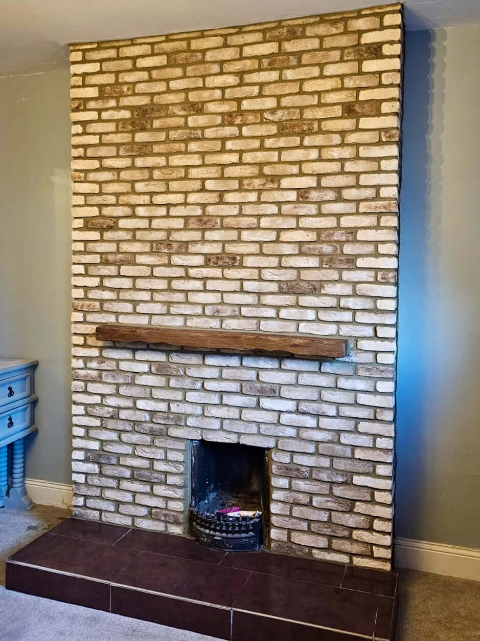 Rustic cream blend brick slips create a stylish fireplace with a wooden mantel in a cozy living room setting.