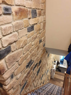 Stone Cladding Antique Blend on a staircase wall, showcasing a natural aesthetic with varied textures and colors.