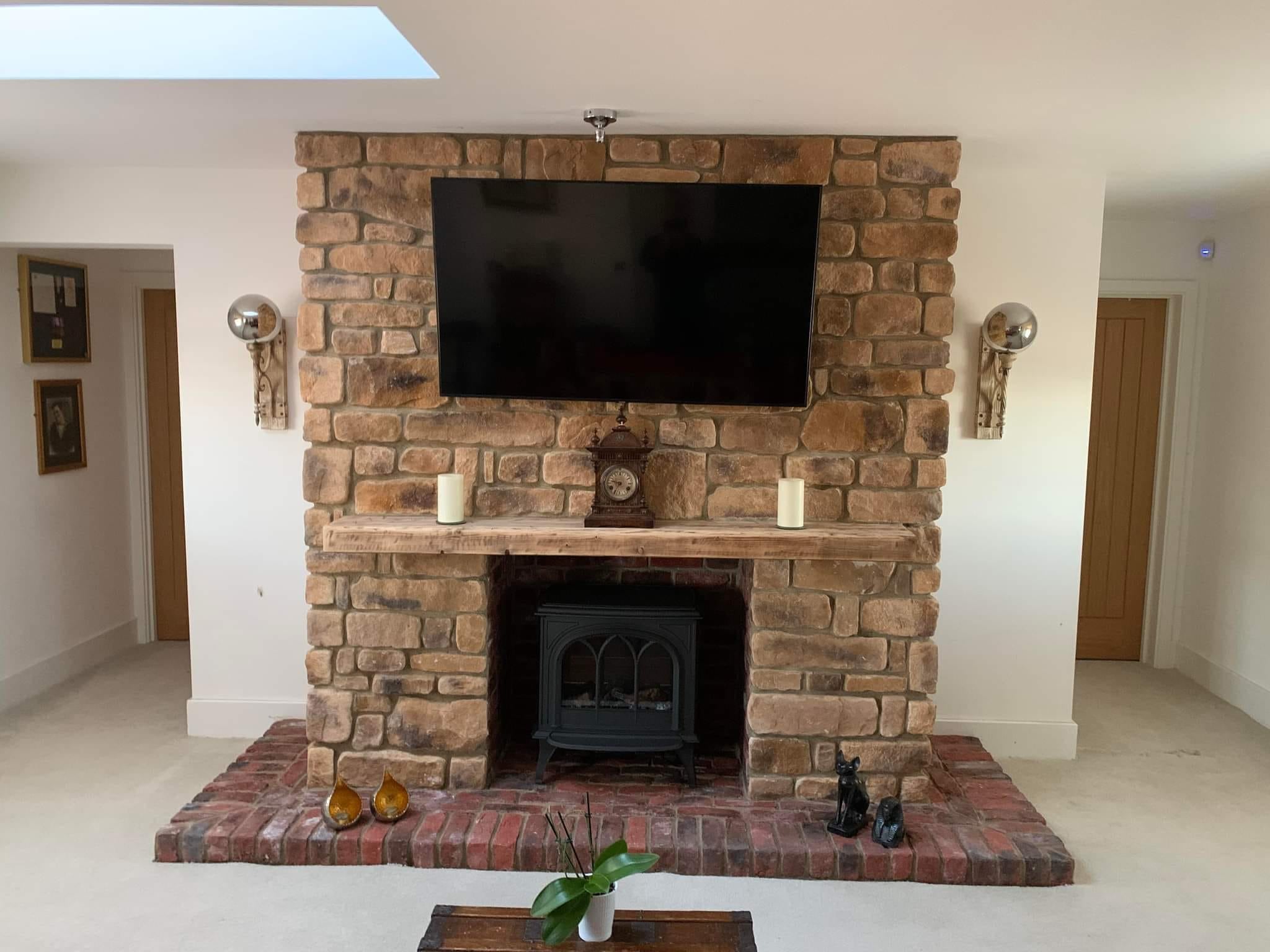 Stone cladding fireplace with rustic burnt buff blend finish, featuring a mounted TV and decorative elements.