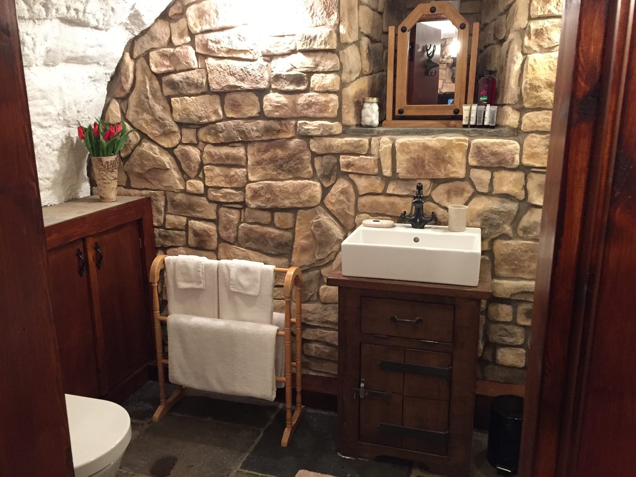 Cozy bathroom featuring Cotswold Blend stone cladding, wooden furniture, and natural decor elements.