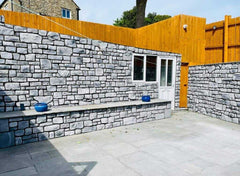 Modern outdoor space featuring light grey stone cladding walls and a wooden fence, showcasing a stylish design.