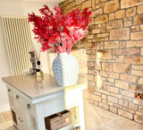 Interior view showcasing stone cladding wall with decorative vase and red foliage. Elegant kitchen design accentuated by natural stone.