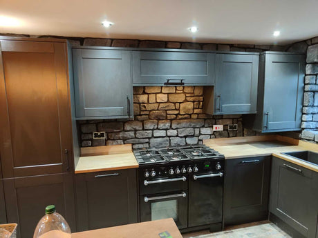 Modern kitchen featuring light grey stone cladding on the wall, enhancing the stylish cabinetry and appliances.
