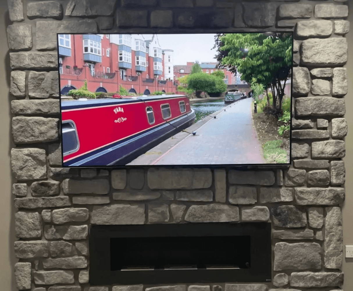 Stone cladding wall featuring a TV above a modern fireplace, showcasing a picturesque canal view.
