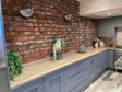 Rustic kitchen with Terrace Red Blend Brick Slips, grey cabinets, wooden countertop, and decorative plants.