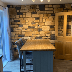 interior view of a kitchen featuring antique blend stone cladding wall and wooden bar top with seating